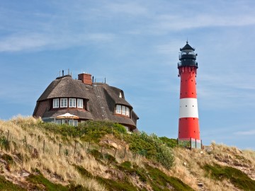 Leuchtturm und Reethaus an der Nordseeküste