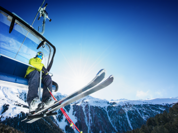 Skifahrer im Skilift vor blauem Himmel