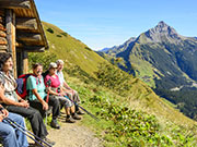 Wanderer machen eine Pause vor einer Berghütte.