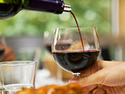 Glas Rotwein Rotwein wird in ein Glas geschüttet.
